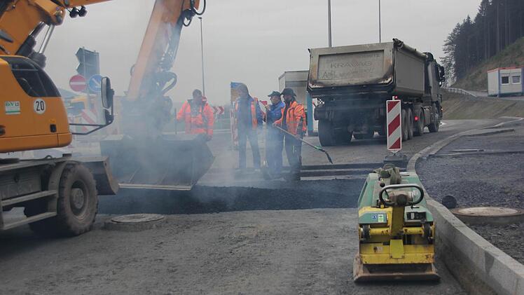 Mit der Baggerschaufel und per Hand wird der Asphalt breit gemacht. Foto: Friedwald Schedel