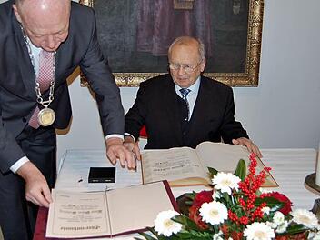 Der langjährige Stadtarchivar Klaus-Dieter Guhling (76) trägt sich unter den Augen von Bürgermeister Helmut Blank ins Goldene Buch der Stadt Münnerstadt ein. Foto: Sigismund von Dobschütz