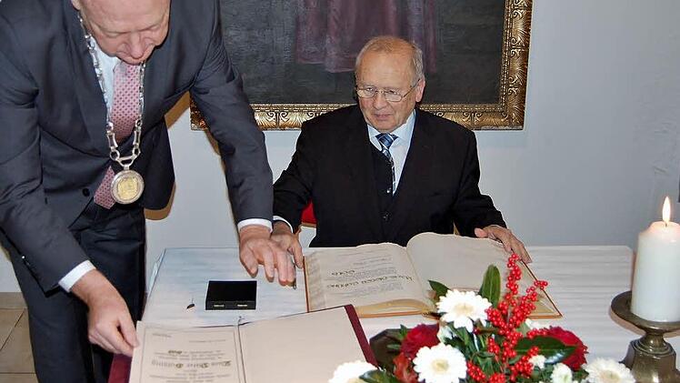 Der langjährige Stadtarchivar Klaus-Dieter Guhling (76) trägt sich unter den Augen von Bürgermeister Helmut Blank ins Goldene Buch der Stadt Münnerstadt ein. Foto: Sigismund von Dobschütz