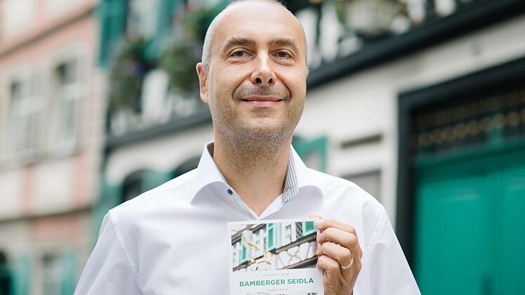 Autor Harry Luck mit seinem neuen Buch vor authentischer Kulisse in der Sandstraße.  Foto: Hendrik Steffens
