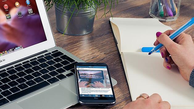 Der Laptop und das Smartphone am Arbeitsplatz können dazu verlocken, die EM 2024 zu schauen.