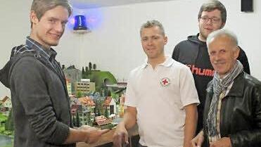 Fabian Wirth (links), Tim Renner (Zweiter von rechts) und der Vorsitzende der Eisenbahnfreunde Lichtenfels, Werner Keidel (rechts), übergeben die Planspielplatte offiziell an Tobias Eismann (Zweiter von links) vom Roten Kreuz.