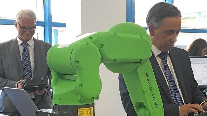 Alexander Tritthart (rechts) versucht sich an dem Roboterarm ebenso wie Schulleiter Martin Wirsching. Nach kurzer Einweisung machten die Arme auch das, was die beiden wollten.  Foto: Michael Busch