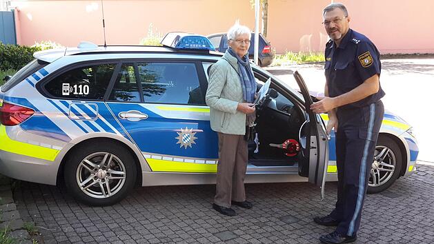 Galant h&auml;lt Herbert Markert (rechts) der 84-j&auml;hrigen Sieglinde Leiding die Autot&uuml;r auf. Mit dem Streifenwagen chauffierte der Bad Br&uuml;ckenauer Polizeichef die Seniorin anschlie&szlig;end zur Kfz-Zulassungsstelle, wo nach freiwilliger Entscheidung ihre Fahrerlaubnis entwertet wurde. Foto: Rolf Pralle