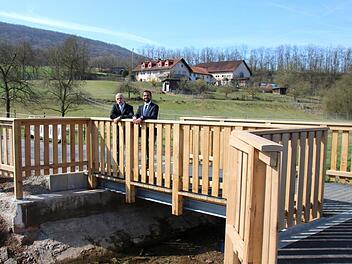 Bürgermeister Kay Blankenburg und Jan Voll, der Leiter des städtischen Bauamtes, sind am Freitagvormittag die ersten, die das neue Bauwerk über den Arnshäuser Lollbach betreten dürfen. Auffällig ist das hohe Geländer. Es soll vor allem die Radfahrer schützen.  Foto: Kathrin Kupka-Hahn