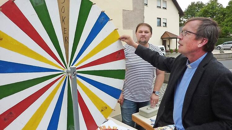 Pfarrer Hans-Michael Dinkel bediente auch das Glücksrad. Mit im Bild Pfarrgemeinderat Christian Fiedler  Foto: Gerd Fleischmann