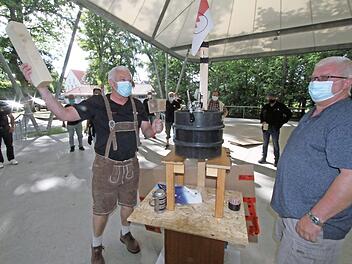 Jürgen Gumbrecht haut den Hammer auf ein Kantholz, dann wird mit moderner Zapfanlage angestochen. Die Kerwasburschen beobachten den "hochoffiziellen Akt" aus entsprechender Entfernung. Fotos: Michael Busch