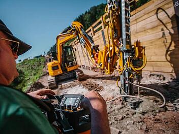 Olaf Eckhardt steuert das Kettenfahrzeug mit dem großen Bohrer unterhalb der B 85. Die Holzwand hält den Schutt zurück.  Fotos: Hendrik Steffens