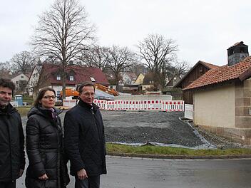 Restaurator Uwe Franke, Freifrau Iris von Künßberg-Schmidt und Peter Hofmann aus Wachholder wollen, dass der Löschwasserbehälter (im Hintergrund) wieder beseitigt wird. Durch den Bau werde das historische Zentrum von Wernstein verschandelt, sagen sie. Rechts im Bild ist das sanierte Backhäuschen zu sehen. Fotos: Jürgen Gärtner