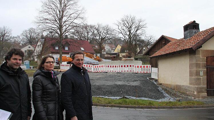 Restaurator Uwe Franke, Freifrau Iris von Künßberg-Schmidt und Peter Hofmann aus Wachholder wollen, dass der Löschwasserbehälter (im Hintergrund) wieder beseitigt wird. Durch den Bau werde das historische Zentrum von Wernstein verschandelt, sagen sie. Rechts im Bild ist das sanierte Backhäuschen zu sehen. Fotos: Jürgen Gärtner