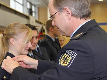 Leitender Polizeidirektor Andreas Poddig von der Bundespolizeiakademie bringt bei Christine Derra die neuen Schulterklappen an. Foto: Martina Straub