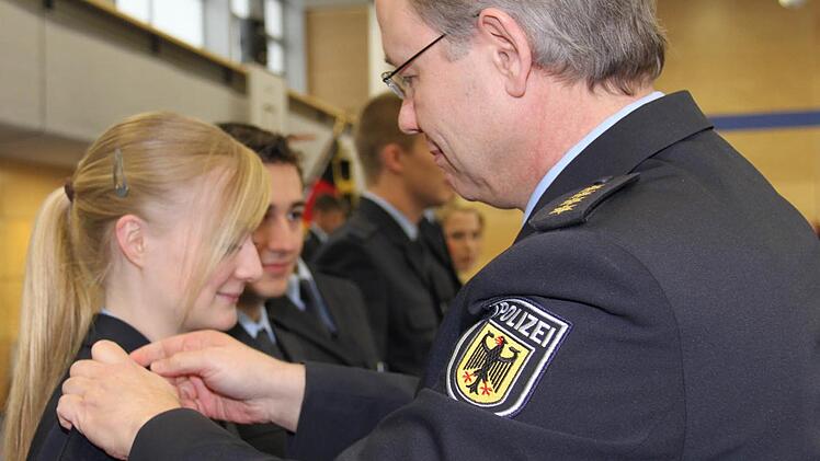 Leitender Polizeidirektor Andreas Poddig von der Bundespolizeiakademie bringt bei Christine Derra die neuen Schulterklappen an. Foto: Martina Straub
