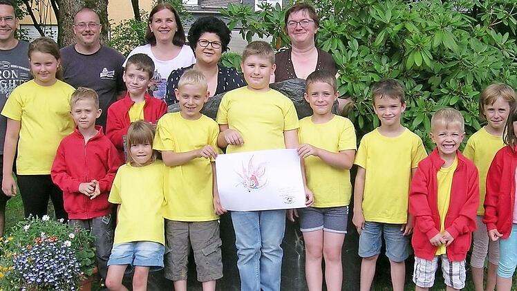 Ein Teil der Reichenbacher "L&ouml;sch-Kids" mit dem Gewinner-Logo und hinten von links: Kommandant Stefan Weber, Christian G&auml;bler, Monika Hager, Kerstin Seitz sowie die Feuerwehr-Vorsitzende und zugleich Leiterin der Kindergruppe, Martina Zwosta. Foto: Heike Sch&uuml;lein