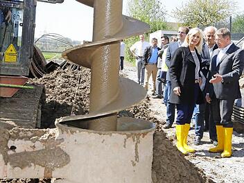 Ein riesiger Bohrer gräbt Löcher an den Stellen in den Untergrund, an denen später Spundwände elf Meter tief in den Boden getrieben werden. Unser Bild zeigt Umweltministerin Ulrike Scharf bei der Baustellen-Besichtigung im Gespräch mit OB Henry Schramm. Fotos: Matthias Hoch