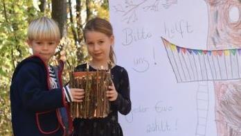 Mit selbst gebastelter Sammelbox und eigens gestaltetem Baumhaus-Banner rühren Joshua und Arianna die Werbetrommel.
