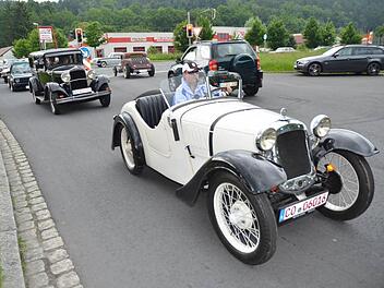 Rassige Karossen bei der Ausfahrt: vorne ein BMW Dixi (weiß, Baujahr 1926), dahinter ein Dodge (Baujahr 1928), rechts hinten an der Ampelanlage ein Chevrolet Hot Rod.