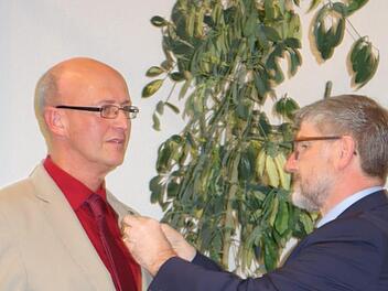 Landrat Michael Busch heftet Xaver Herr die Verdienstmedaille des Verdienstordens der Bundesrepublik Deutschland an.Foto: Lothar Weidner