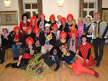 Pfarrer Cibura (Mitte, mit Helm) im Kreis der "Sandhos'n"-Frauen, die in Kostümen der letzten drei Jahre kamen, mit Musiker Christian (rechts) Foto: Robert Polster