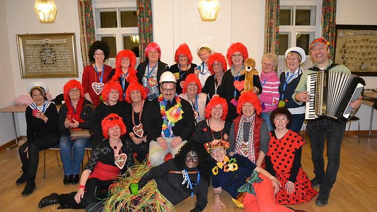 Pfarrer Cibura (Mitte, mit Helm) im Kreis der "Sandhos'n"-Frauen, die in Kostümen der letzten drei Jahre kamen, mit Musiker Christian (rechts) Foto: Robert Polster