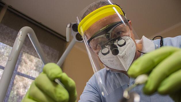 Zahnarzt Oldrich Havelka in Vollmontur: Bei manchen Behandlungen reichen FFP2-Maske und Schutzbrille nicht aus. Dann muss er zus&auml;tzlich ein Plexiglasvisier vor dem Gesicht tragen, das ihn vor Aerosolen sch&uuml;tzt.  Foto: Dominic Buckreus