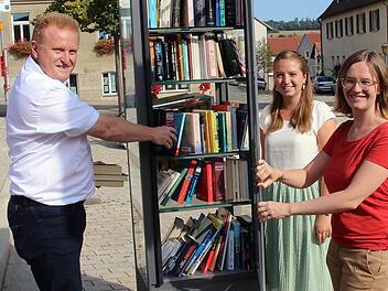Dieser Bücherschrank steht auf dem Maßbacher Marktplatz. Jeder darf Bücher entnehmen und hineinstellen. Zur Inbetriebnahme kamen Bürgermeister Matthias Klement (links, Allianzmanagerin Hannah-Rabea Grübl (rechts) und ihrer Praktikantin Miriam Mai.  Foto: Dieter Britz