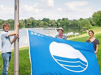 Martin L&uuml;ders (Freizeit GmbH), Anne Schmitt (Flussparadies Franken) und Anne-Maria Schneider (Kur- & Tourismus-Service) beim Hissen der Blauen Flagge am Ostsee Bad Staffelstein.  Foto: Flussparadies Franken