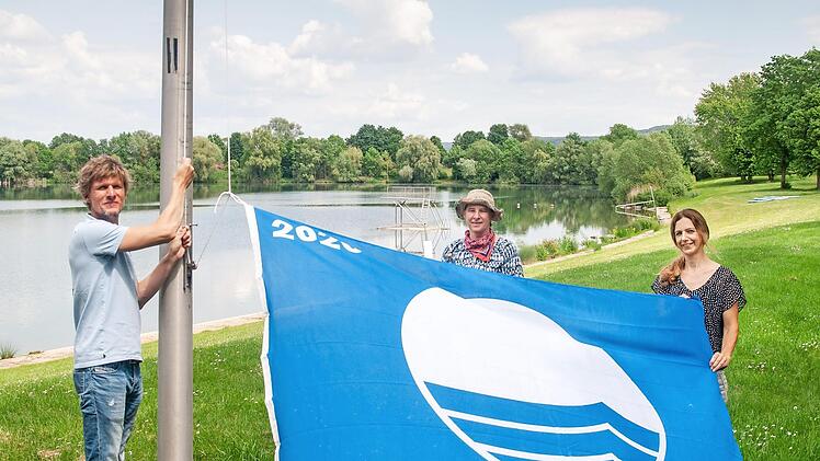 Martin L&uuml;ders (Freizeit GmbH), Anne Schmitt (Flussparadies Franken) und Anne-Maria Schneider (Kur- & Tourismus-Service) beim Hissen der Blauen Flagge am Ostsee Bad Staffelstein.  Foto: Flussparadies Franken