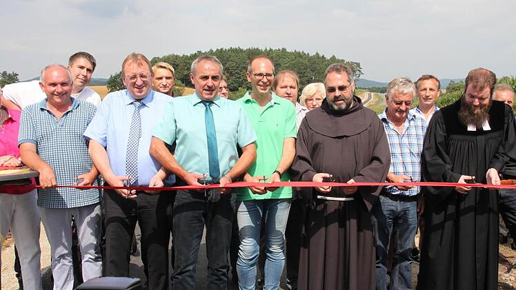 Darf bei einer Straßeneinweihung nicht fehlen: Das obligatorische Zerschneiden des roten Bandes, mit der der Wirtschaft-, Geh- und Radweg zwischen Prügel und Maineck seiner offiziellen Bestimmung übergeben wurde. Foto: Stephan Stöckel.