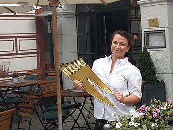 Julia Humpert, Mitarbeiterin im "Goldenen Kreuz", hält die heruntergefallene Metall-Fahne in Händen - und kann auch schon wieder lächeln, denn bei dem "Vorfall" wurde niemand verletzt. Foto: Coburger Tageblatt