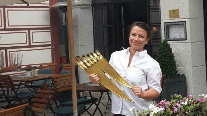 Julia Humpert, Mitarbeiterin im "Goldenen Kreuz", hält die heruntergefallene Metall-Fahne in Händen - und kann auch schon wieder lächeln, denn bei dem "Vorfall" wurde niemand verletzt. Foto: Coburger Tageblatt