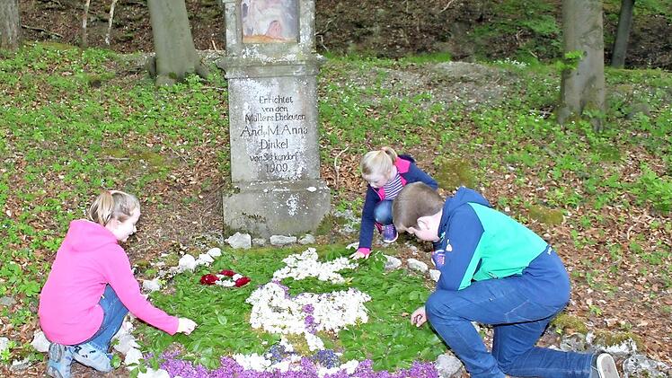 Jakob (12), Eva-Maria (10) und Katharina (7) schmücken den Bildstück oberhalb von Serkendorf für die Wallfahrer.