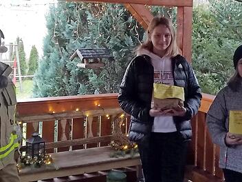 Die Jugend- und Kinderfeuerwehr D&ouml;rfles bemalte Stern-Weihnachtskarten mit winterlichen Motiven. Die Leiterin der "Feuerwehrbande" D&ouml;rfles, Geli Kempf (linkes Foto, l.), beschenkt Zoe und Kimara H&ouml;fner, aktive Mitglieder der Jugend- und Kinderfeuerwehr D&ouml;rfles. Die bunten Weihnachtsgr&uuml;&szlig;e sind auf dem rechten Foto zu sehen. Fotos: privat