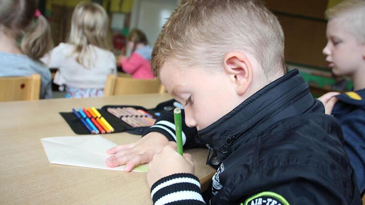Leo beim Ausmalen einer Papier-Schultüte.