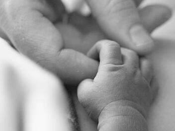 Abschied vom Sternenkind: Eine Erwachsenenhand berührt kleine, leblose Finger. Vom Aussehen her erinnert das Bild an ein Foto aus einem normalen Baby-Shooting.  Foto: Kai Gebel/Dein-Sternenkind