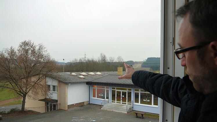 Da ist das Ding: Bürgermeister Markus Mönch zeigt auf das Turnhallendach, durch das die Wärme mehr oder weniger ohne bremsende Isolation hinaus in die Landschaft pfeift. Foto: Berthold Köhler