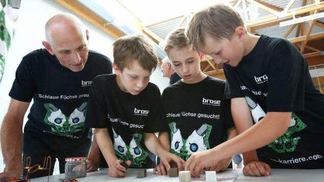 Wolfgang Heyder, Leiter Nachwuchskonzept Brose Baskets, mit drei Schülern beim Experiment zu Magnetismus.
