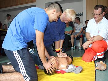 Ahmet Bozhügük und Michael Frank üben die Herz-Lungen-Wiederbelebung an einer Simulationspuppe. Frank Schmidt vom Coburger BRK leitet sie dabei an (von links). Foto: Helke Renner
