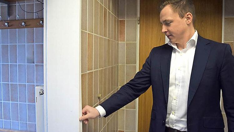 Philipp Greiner zeigt die Türrahmen in den Sanitärräumen der ASV Sportanlage, die wegen der dauernden Feuchtigkeit verquollen sind.
