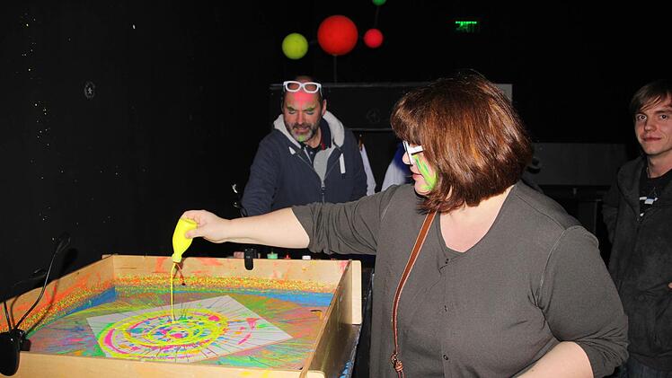 Claudia lässt Leuchtfarbe auf die Drehscheibe tropfen. So entsteht unter Schwarzlicht ein Kunstwerk.  Foto: Diana Fuchs