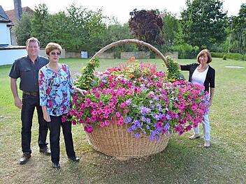 Der mit Blumen geschmückte Korb am Höllein-Platz. Über ihn freuen sich von links Zweiter Bürgermeister Ralf Reisenweber sowie die beiden Vorsitzenden des Obst- und Gartenbauvereins, Christine Partheymüller und Rita Vogel (r.).  Foto: Thomas Micheel