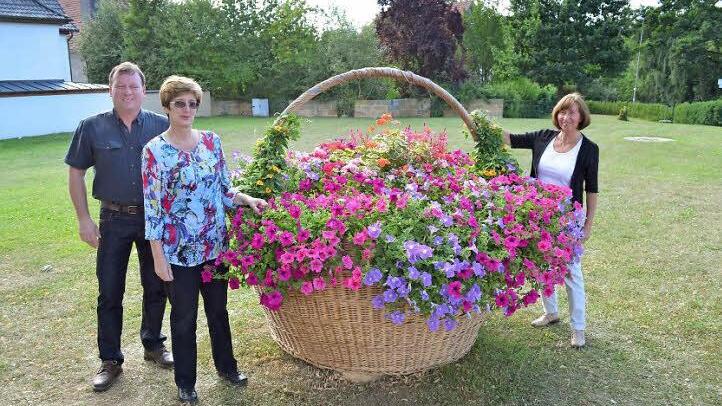 Der mit Blumen geschmückte Korb am Höllein-Platz. Über ihn freuen sich von links Zweiter Bürgermeister Ralf Reisenweber sowie die beiden Vorsitzenden des Obst- und Gartenbauvereins, Christine Partheymüller und Rita Vogel (r.).  Foto: Thomas Micheel
