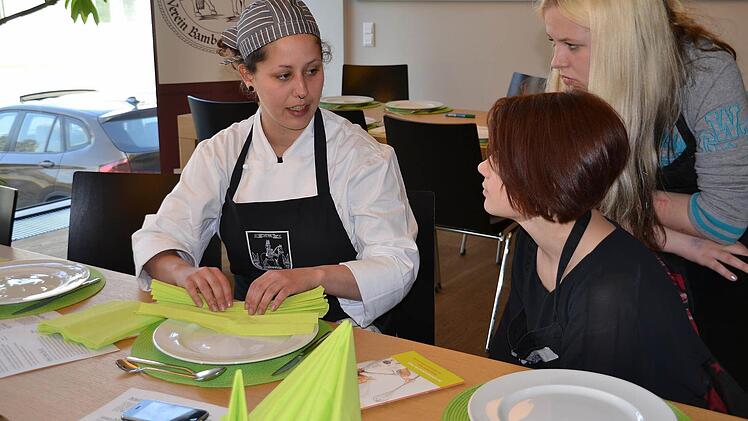 Auszubildende Nicole Gomes da Silva Morais (links) stand den Mädchen beim Falten der Servietten Rede und Antwort