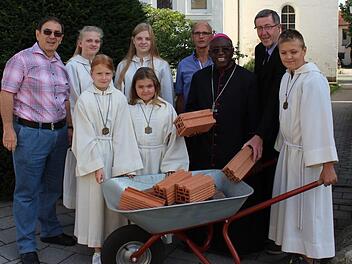 Bausteine symbolisieren die Spenden für die Erweiterung der Schule in Biharamulo/Tansania. Im Bild: Werner Baier (links) mit einer Ministrantengruppe, Kirchenpfleger Herbert Dotterweich, Bischof Severine und Pfarrer Wolfgang Schmidt  Foto: Evi Seeger