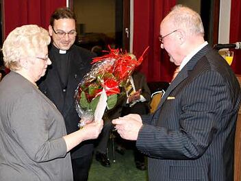Kirchenpfleger Georg Simon überreichte der langjährigen Pfarrsekretärin Mathilde Wunder einen Blumenstrauß. Im Hintergrund Pfarrer Richard F. Reis.  Foto: Michael Wunder