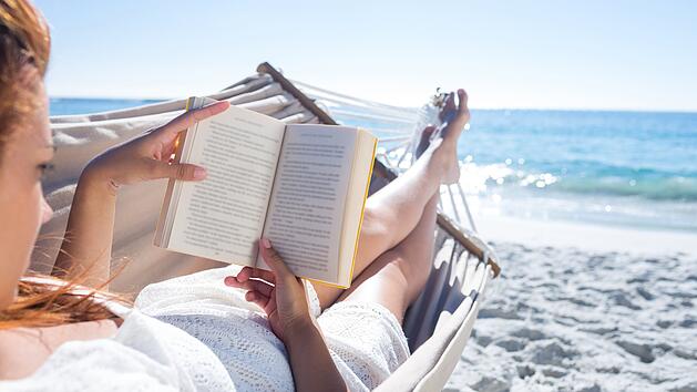 Frau liest im Urlaub am Strand