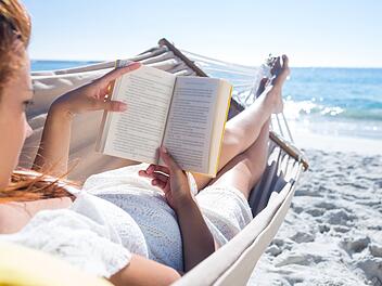 Frau liest im Urlaub am Strand
