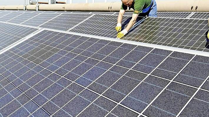 Auf dem Symbolbild arbeiten Mitarbeiter einer Umweltfirma an Photovoltaik-Paneln, die auf einem Dach angebracht sind. Foto: Holger Hollemann dpa/lni