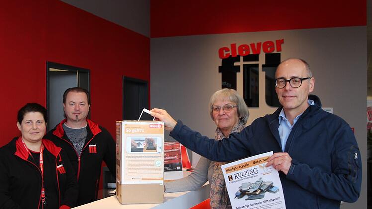 Pavla und Andreas Gebhardt haben zur Freude von Marga Labandowsky und Christoph Heitzer in ihrem Fitnessstudio Clever-fit einen der Sammelbeh&auml;lter f&uuml;r die Spendenaktion "Handys recyceln - Gutes tun" aufgestellt. Foto: Theresa Schiffl