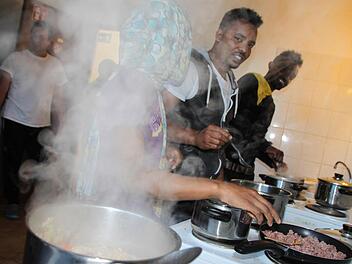 Eine junge, äthiopische Frau, die nicht genannt werden will, kocht zusammen mit Waleligne Zerga Degu (Mitte) und Daniel Eliyas (beide aus Äthiopien) in der Gemeinschaftsküche der Unterkunft. Foto: Ulrike Müller