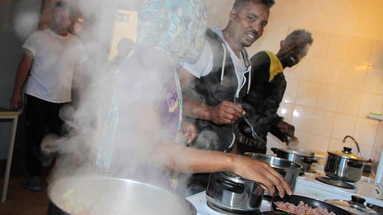 Eine junge, äthiopische Frau, die nicht genannt werden will, kocht zusammen mit Waleligne Zerga Degu (Mitte) und Daniel Eliyas (beide aus Äthiopien) in der Gemeinschaftsküche der Unterkunft. Foto: Ulrike Müller